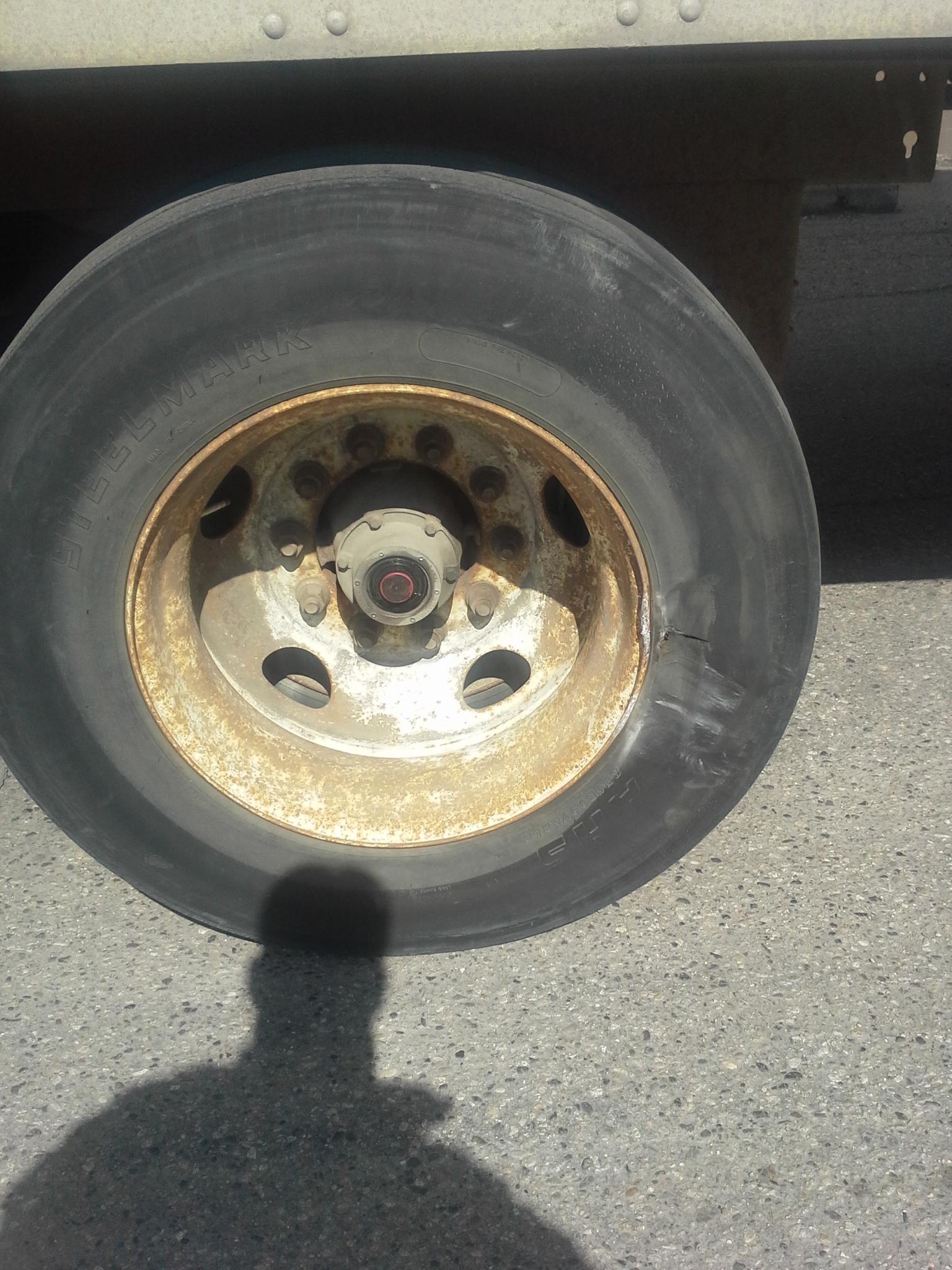 A damaged semi-trailer tire where the driver struck a concrete barrier. The concrete barrier bent the semi-trailer tire rim.