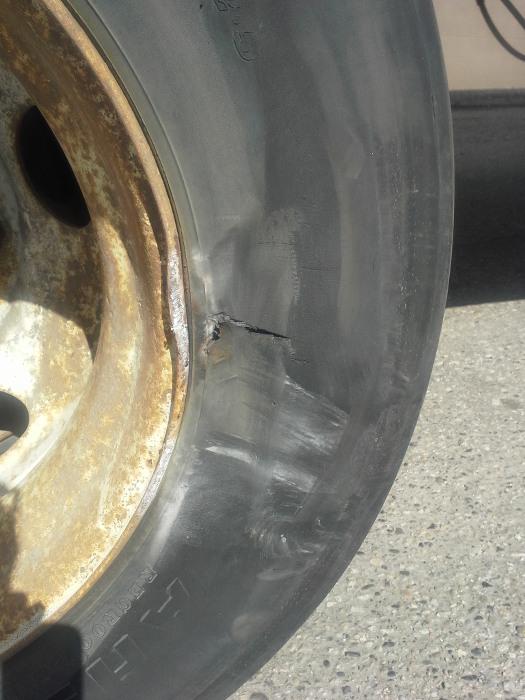 A tire and rim sustains damage after a student fails to make a wide enough turn and crashes with a concrete barrier.
