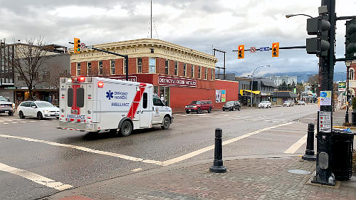 An ambulance moving through a red light with traffic stopped at all entry points.