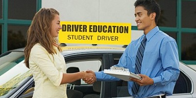 A driving instructor congratulates his student on passing her road test first time.
